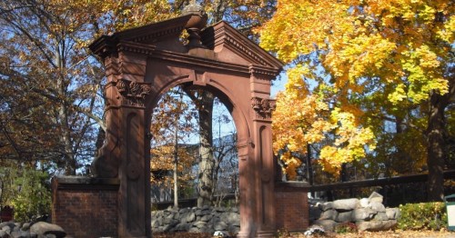 A decorative archway surrounded by vibrant autumn foliage and trees.