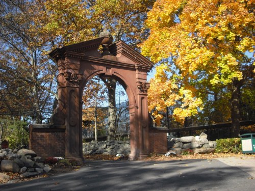 A decorative archway surrounded by vibrant autumn foliage and stone landscaping.