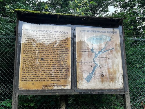Signboard detailing the geological history of the gorge and a map of the Whitewater Gorge, surrounded by greenery.