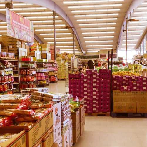 A grocery store aisle filled with shelves of products, including snacks, canned goods, and fresh produce.