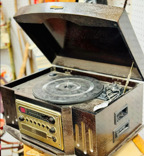Vintage wooden record player with a radio, featuring a turntable and retro design, displayed with an open lid.