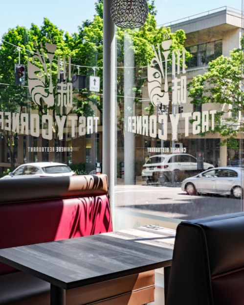 A cozy restaurant interior with a table by a large window, showcasing a view of the street outside.