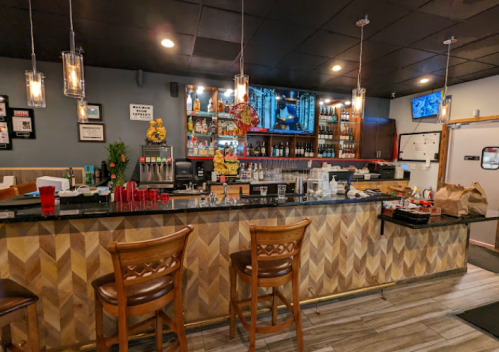 A modern bar with wooden stools, a variety of drinks, and a TV, featuring a stylish chevron-patterned counter.