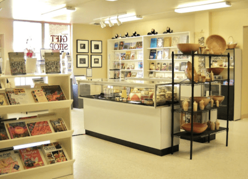 A gift shop interior featuring display cases, shelves of books, and decorative pottery on stands.
