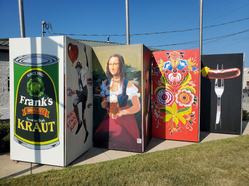 Colorful murals on large boxes, featuring a can of kraut, a woman with a beer, and decorative floral designs.