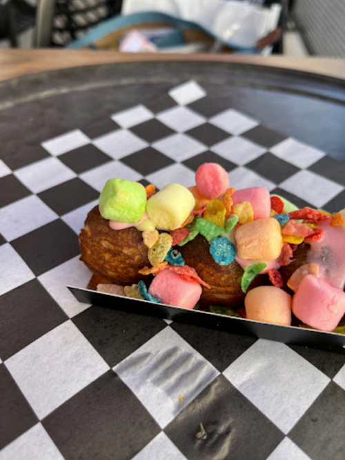 A close-up of a dessert topped with colorful cereal and marshmallows on a checkered paper plate.