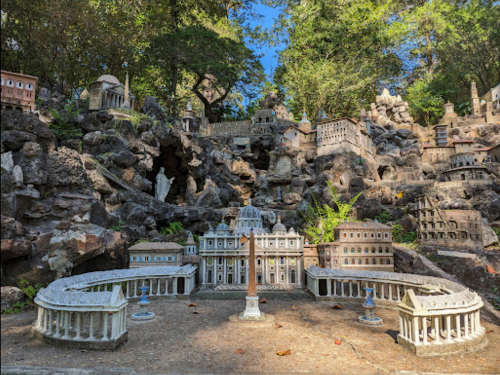 A miniature replica of famous buildings set among rocks and greenery, showcasing intricate architectural details.