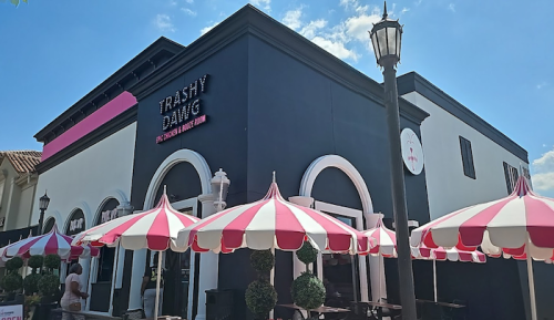 A colorful restaurant with a black and white exterior, featuring red and white striped umbrellas outside.