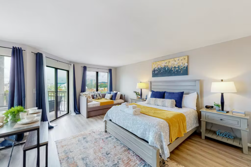 Bright, modern bedroom with a king bed, cozy seating area, and large windows showcasing a scenic view.