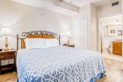 Cozy bedroom with a large bed, two lamps, and an adjoining bathroom visible in the background.