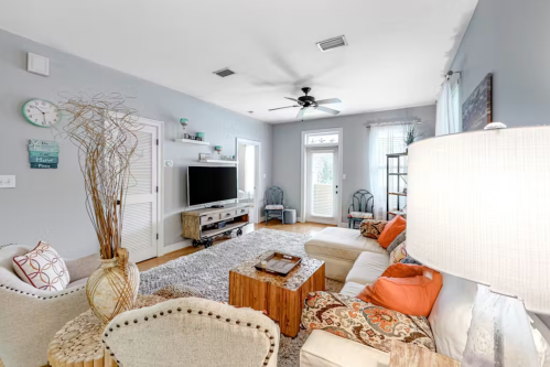 Cozy living room with a light gray color scheme, comfortable seating, a TV, and decorative accents.