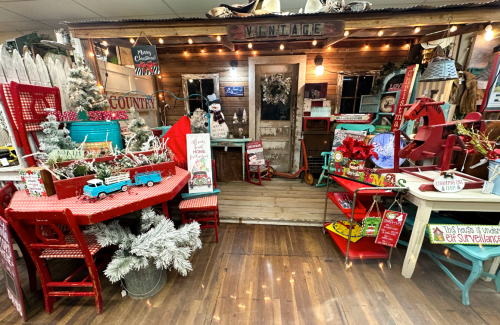 A cozy vintage-themed shop display with festive decorations, including a Christmas tree, red furniture, and holiday signs.