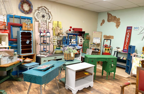 A cozy vintage shop filled with colorful furniture, decor items, and rustic accents arranged in a warm, inviting space.