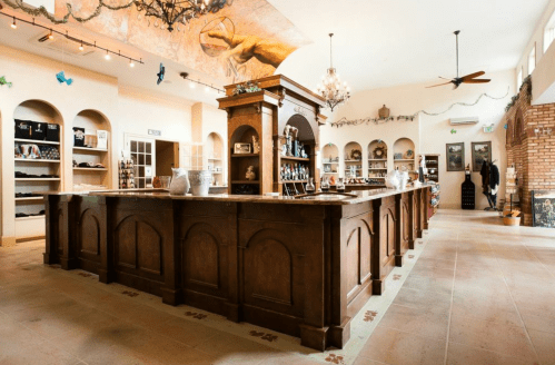 A spacious, elegantly designed shop interior featuring a wooden counter, shelves of products, and decorative elements.