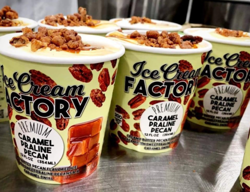 Four tubs of Ice Cream Factory's Caramel Praline Pecan ice cream, topped with crunchy pecans, on a silver surface.