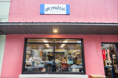 Exterior of Dr. Music Records store, featuring a large window displaying vinyl records and music merchandise.