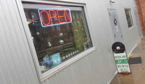 A storefront with an "OPEN" neon sign and a sign for Central House Records, featuring a vinyl record.