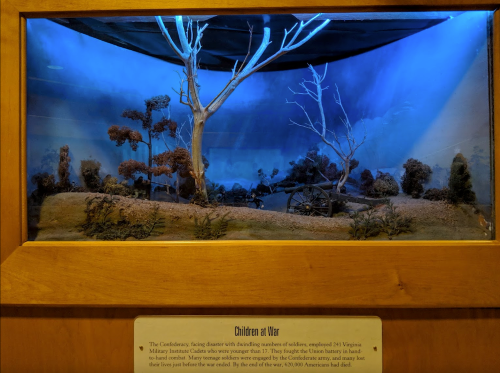A diorama depicting a Civil War scene with trees, a cannon, and a blue-lit background, labeled "Children at War."