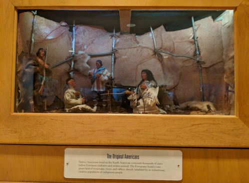 A diorama depicting Native Americans in traditional attire, showcasing their culture and lifestyle.