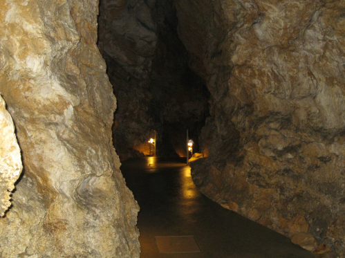 A dimly lit cave pathway with rocky walls and lanterns illuminating the way.