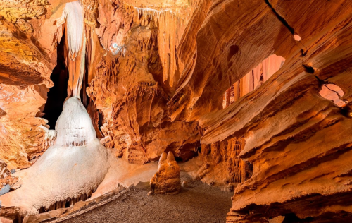 A stunning cave interior featuring unique rock formations and stalactites in warm, earthy tones.