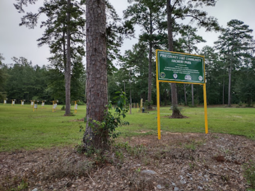 Sign for Pink County Lake Community Archery Park, surrounded by trees and grassy area.
