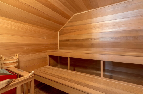 A wooden sauna interior featuring benches and a warm, inviting atmosphere.