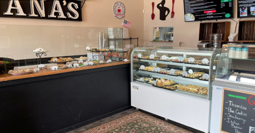 A cozy bakery display featuring a variety of pastries and desserts, with a chalkboard menu and American flag decor.