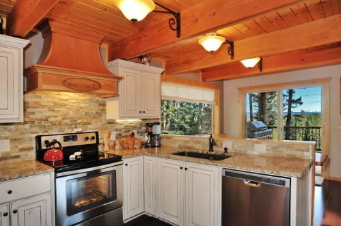 Cozy kitchen with wooden beams, granite countertops, stainless steel appliances, and a scenic view through the window.
