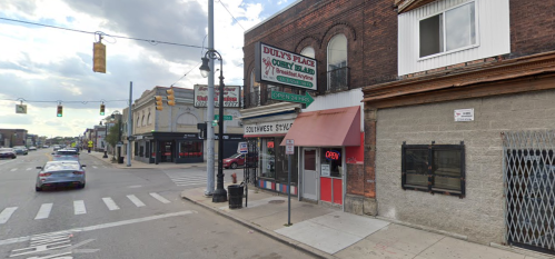 A street view of Duly's Place, a diner with a red and white exterior, located on a busy urban corner.