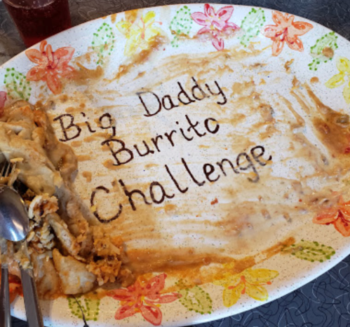 A colorful plate with remnants of food, featuring the words "Big Daddy Burrito Challenge" written in sauce.