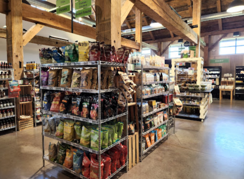 A spacious store interior featuring shelves stocked with various snacks and grocery items, showcasing wooden beams.