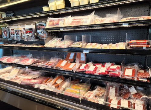 A refrigerated display case filled with various packaged meats and deli products.