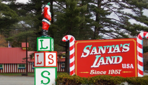 A colorful sign for Santa's Land USA features a Santa statue and festive candy canes, established in 1957.