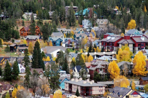 Aerial view of a colorful mountain town with autumn foliage and a mix of houses and buildings.