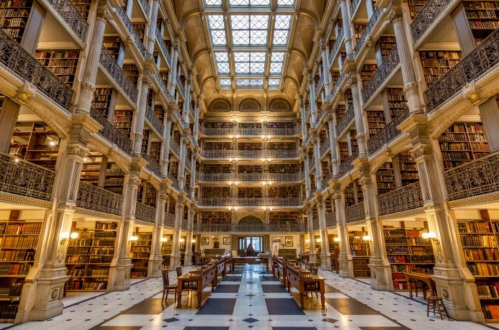 A grand library interior with tall bookshelves, elegant architecture, and a skylight illuminating the space.