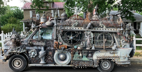 A creatively decorated van covered in various metal objects and sculptures, showcasing an eclectic artistic style.