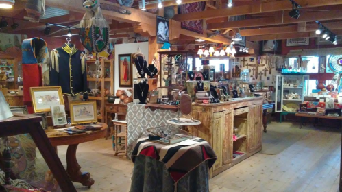 A cozy shop interior filled with handmade crafts, jewelry, and artwork, featuring wooden displays and warm lighting.