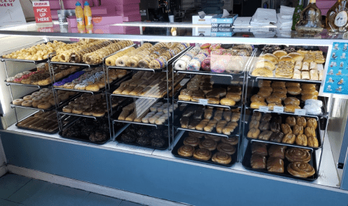 A display case filled with a variety of donuts and pastries, arranged on multiple shelves.