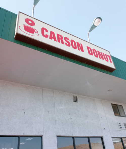 Sign for "Carson Donut" on a building, featuring a donut graphic and a star, under a clear blue sky.