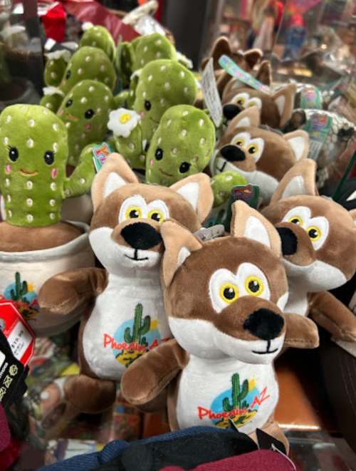 A collection of plush toys, including cacti and cartoonish coyotes, displayed in a store.