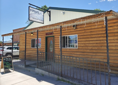 A rustic wooden building with a sign reading "9 Peaks Restaurant & Lounge" and a welcoming entrance.