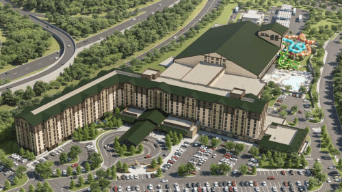 Aerial view of a large hotel complex with a water park, surrounded by trees and parking areas.