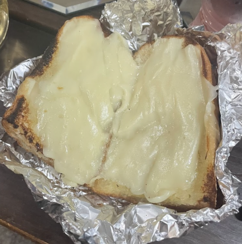 A piece of toasted bread topped with melted cheese, wrapped in aluminum foil.