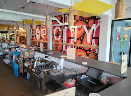 A vibrant bar area with a colorful mural, shelves of drinks, and a modern counter setup.