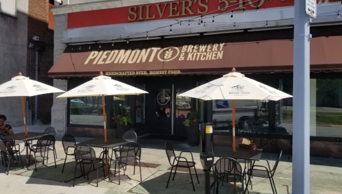 Outdoor seating area of Piedmont Brewery & Kitchen, featuring umbrellas and tables in front of the restaurant.