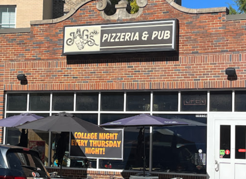 Exterior of J&G's Pizzeria & Pub with a sign for "College Night Every Thursday Night!" and outdoor seating.