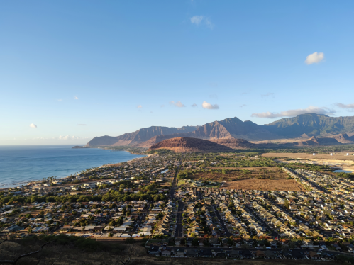 Aerial view of a coastal town with mountains in the background and a clear blue sky.