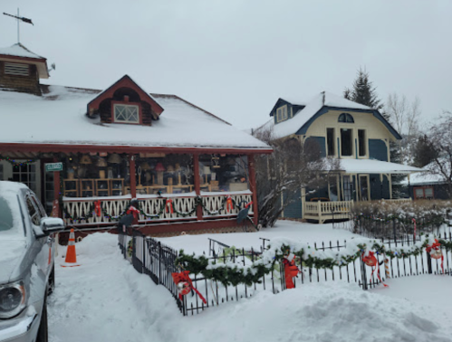 A snowy scene featuring two charming houses decorated for Christmas, with festive garlands and snow-covered yards.