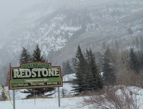 Welcome sign for Redstone National Historic District, surrounded by snow-covered trees and foggy mountains.